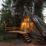 森の中に建つコンパクトなAフレームの山小屋の外観　夕暮れ