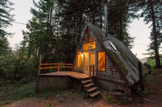 森の中に建つコンパクトなAフレームの山小屋の外観　夕暮れ