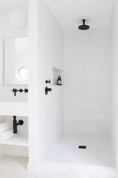 マットなブラックの水栓金物を用いた白いタイル張りのバスルーム1