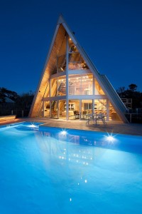 海沿いに建つガラス張りの三角の家のプルーサイドの夜景