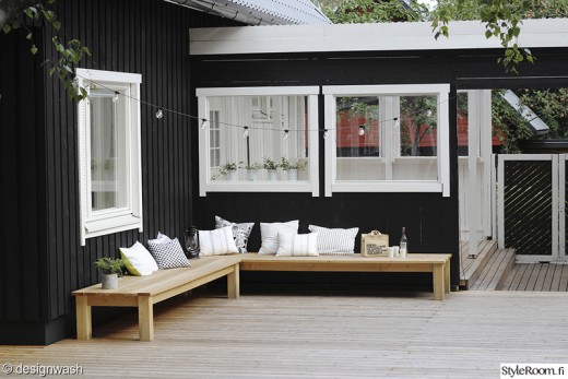 L字型に配置された木製の低いデイベッドのあるウッドデッキの屋外リビング1