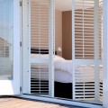 白い木製の折れ戸鎧戸で庭とつながるベッドルーム1