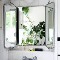 ビンテージの壁掛け三面鏡のある白いタイル貼りのバスルーム