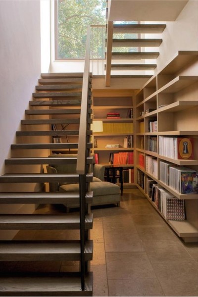 階段下に作り込まれたリーディングヌック　大きな造作本棚と座り心地の良さそうな一人掛けのソファ