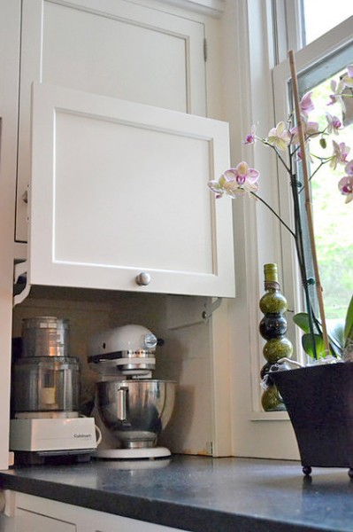 キッチンカウンターの端の壁に埋め込まれた平行にスイングアップする扉付きの中型調理器具収納スペース.jpg